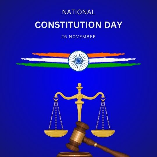 Graphic for National Constitution Day in India Featuring a Pair of Golden Scales of Justice in the Foreground, with a Stylized Ashoka Chakra Floating Above an Indian Flag-colored Horizontal Stripe on a Deep Blue Background. the Text Reads 'NATIONAL CONSTITUTION DAY 26 NOVEMBER'.