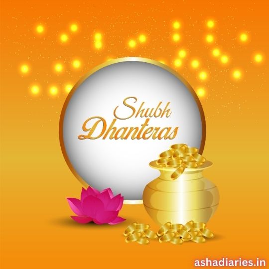 the Image Shows a Festive Greeting for Dhanteras with "shubh Dhanteras" Written in Golden Text at the Center. the Background is Bright Orange with Sparkles, and a Pot Filled with Gold Coins is Placed Next to a Pink Lotus. the Image Also Includes the Website Name "ashadiaries.in" at the Bottom Right Corner.