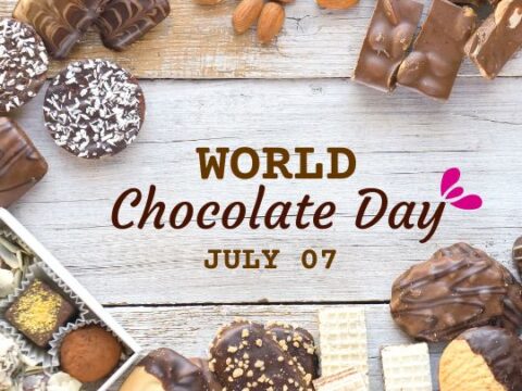 An assortment of chocolates and nuts on a wooden surface with text "WORLD Chocolate Day JULY 07" displayed above.
