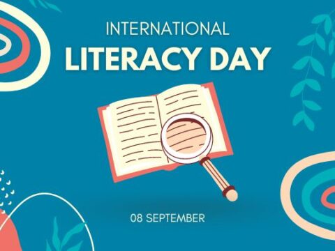 International Literacy Day promotional graphic featuring a stylized open book with pages that appear to flutter, accompanied by a magnifying glass on a vibrant blue background with abstract red swirls and green foliage accents. The text announces '08 September' as the date for the event.