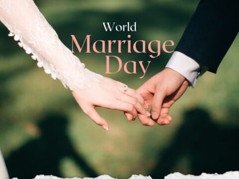 The image depicts a close-up of two people holding hands, one wearing a wedding dress and the other in a suit, symbolizing marriage. The text "World Marriage Day" is prominently displayed over the image. The background is slightly blurred, highlighting the couple's hands and the text. The image has a torn paper effect at the bottom.