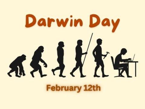 An illustration depicting the evolution of humans, from an ape-like ancestor to a modern human sitting at a desk with a computer. The image is labeled "Darwin Day" in large orange text at the top, with "February 12th" written below it. The URL "ashadiaries.in" is displayed at the bottom right corner.